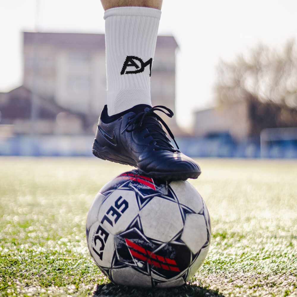 Șosete antiderapante grip ADM purtate cu încălțăminte sport pe terenul de fotbal